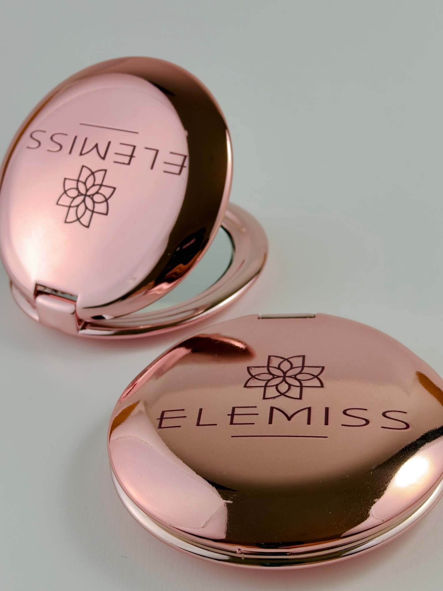 Due specchietti pieghevoli rosa metallizzato, uno aperto e uno chiuso, con il logo Elemiss stampato in UV sul coperchio